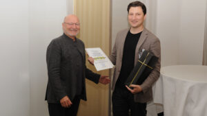 Dr. Bernd Reiss (l.) überreicht die Urkunde an PD Dr. Alexey Unkovskiy, M. Sc. (Charité Berlin), der als Hauptautor und stellvertretend für das Team einen der beiden AGK+ Forschungspreise entgegennimmt